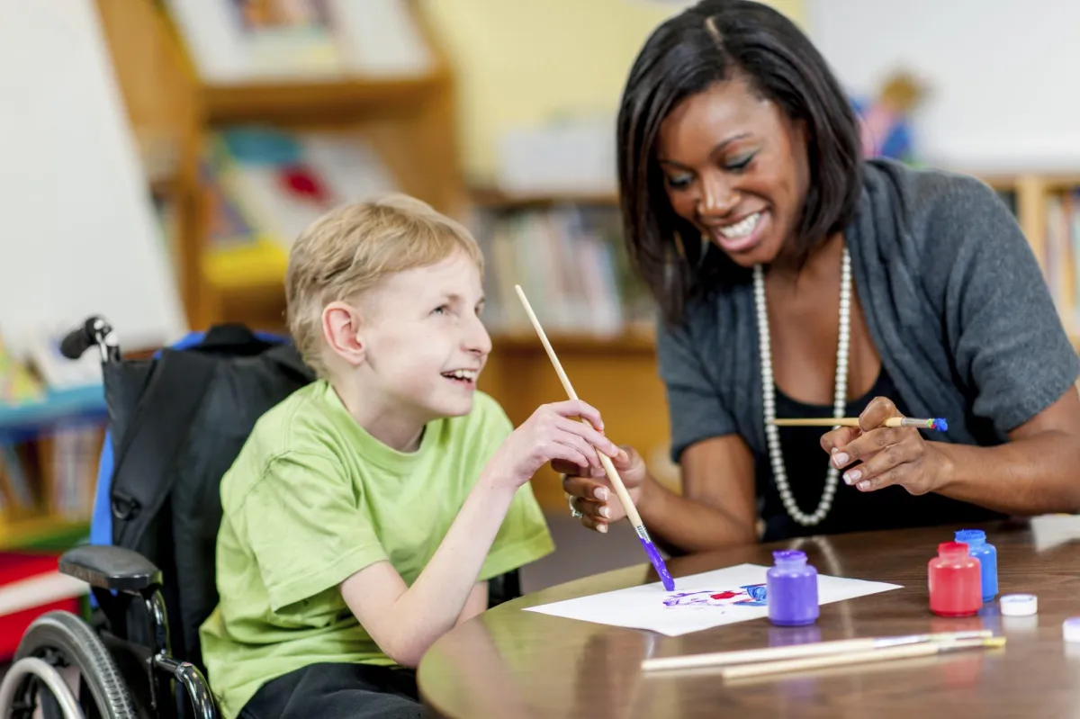 Child painting with teacher